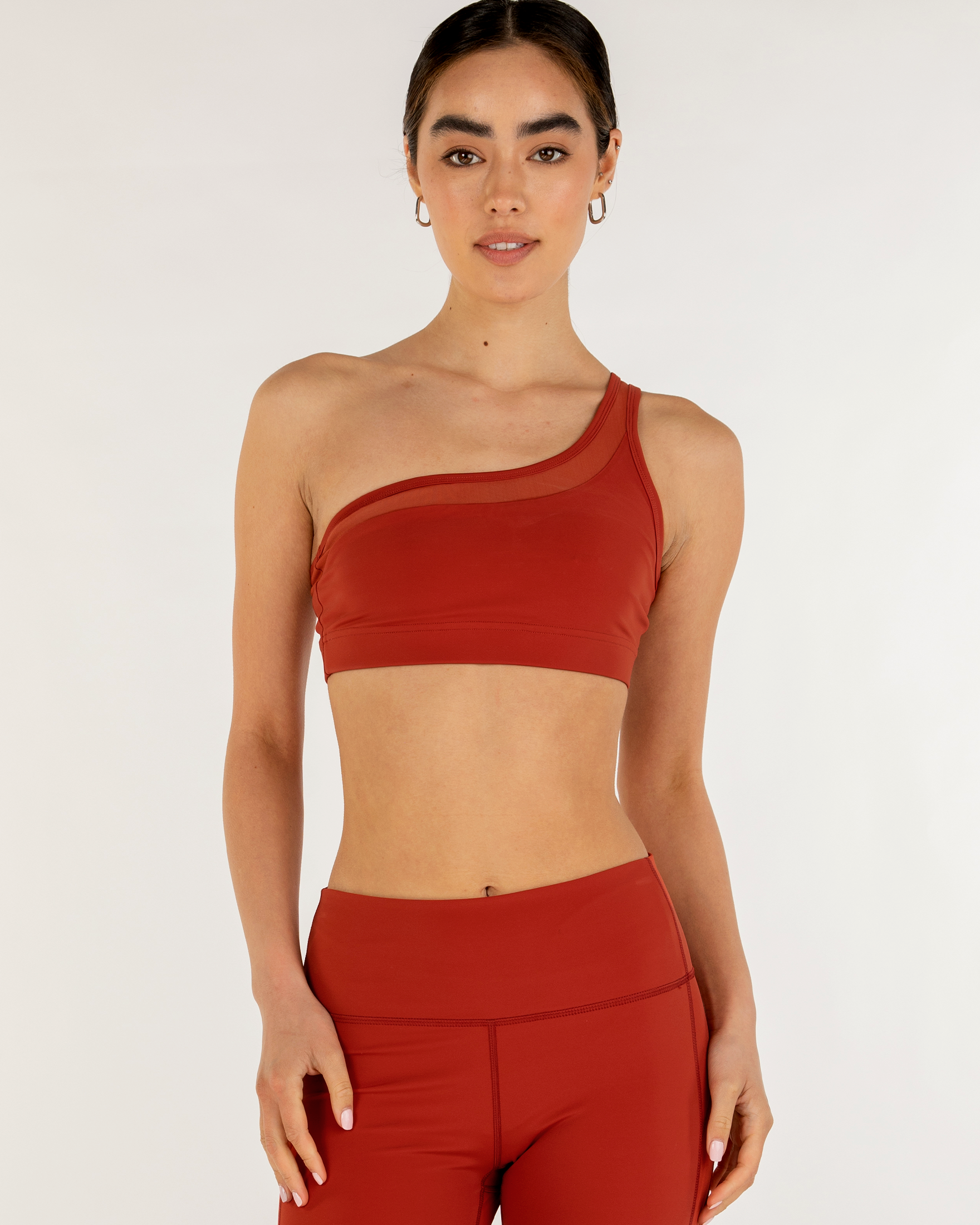Model wearing the Narevia One-Shoulder Mesh Bra in red, showcasing the sheer mesh inset and sleek Silkiflex™ fabric.