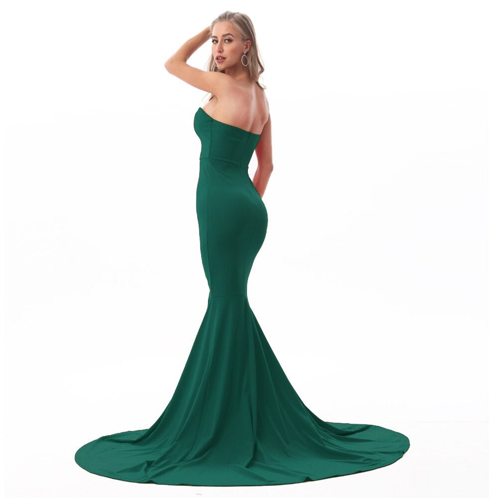 Woman wearing a green strapless mermaid gown with a long, elegant train, perfect for formal events like galas or weddings.