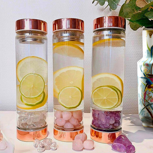 Rose gold glass bottles with lemon slices and gem infusers, featuring eco-friendly borosilicate glass and stainless steel caps.