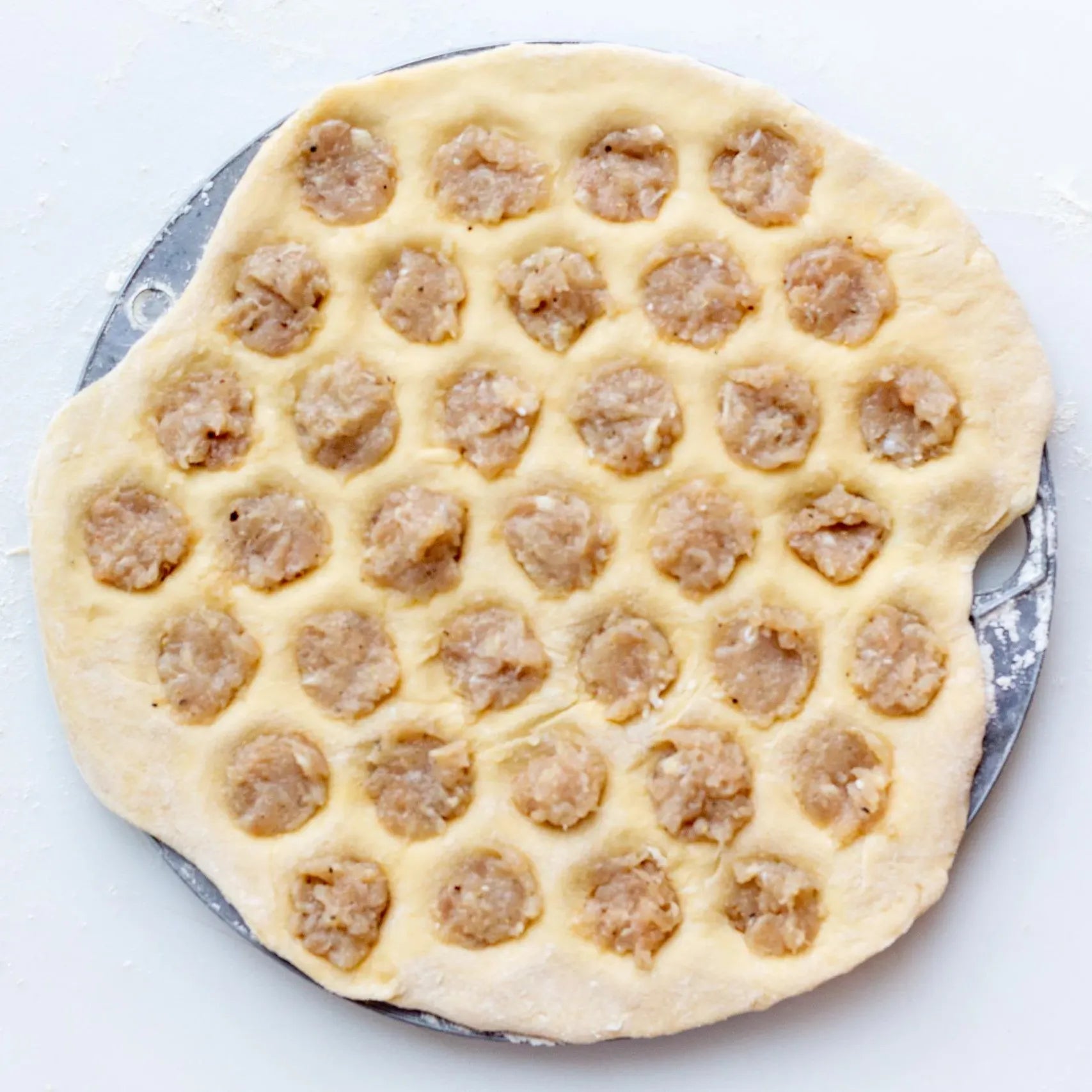 Preparing homemade Ukrainian pelmeni with meat filling on a dough sheet. Traditional dumplings ready to be frozen.