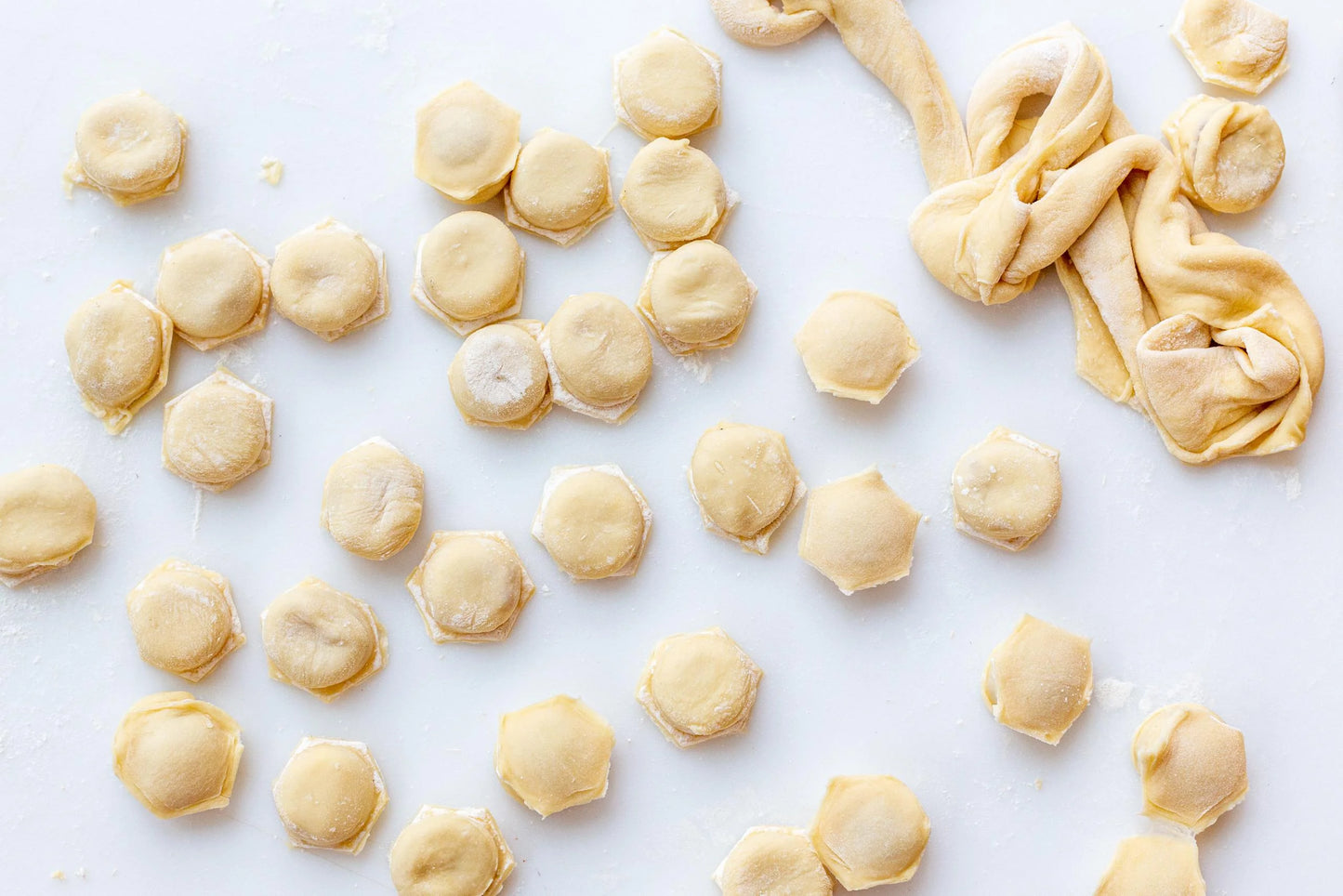 Homemade Ukrainian pelmeni dumplings made with thin dough and various meat fillings, displayed on a white surface.