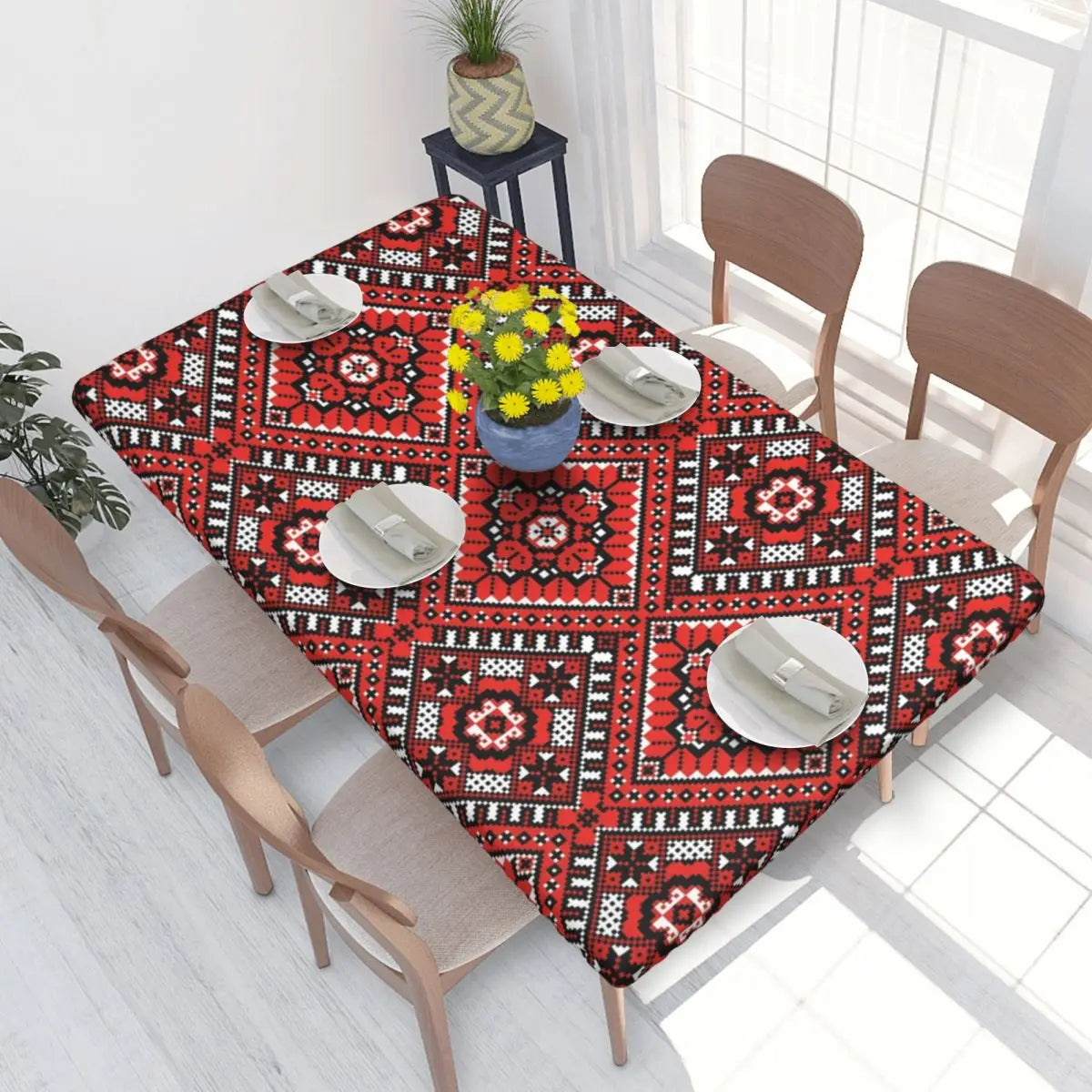 Ukrainian embroidery table cover on dining table with vibrant red and black patterns, set for four with yellow flower centerpiece.