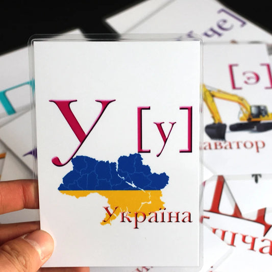 Ukrainian alphabet flashcard held in hand, featuring letter and map design for kids' learning and development.