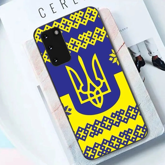 Vyshyvanka and Tryzub Samsung phone case, high-quality black TPU, Ukrainian cultural design, on a book and fabric background.