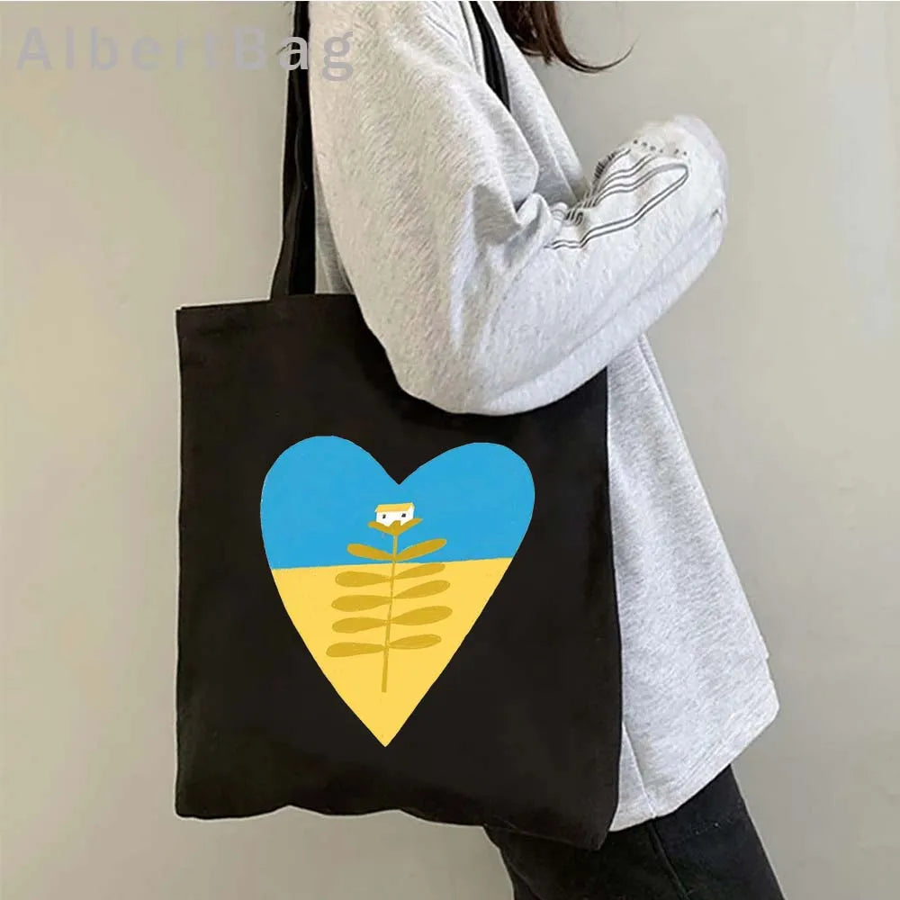 Ukrainian Patriotic Grocery Tote Bag with heart design on person, eco-friendly and reusable, made from lightweight cotton.