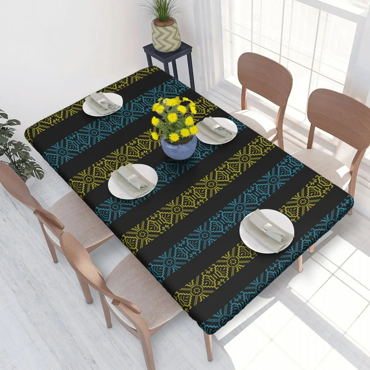 Ukrainian embroidery table cover on dining table with vibrant blue and yellow patterns, set with plates and yellow flowers.