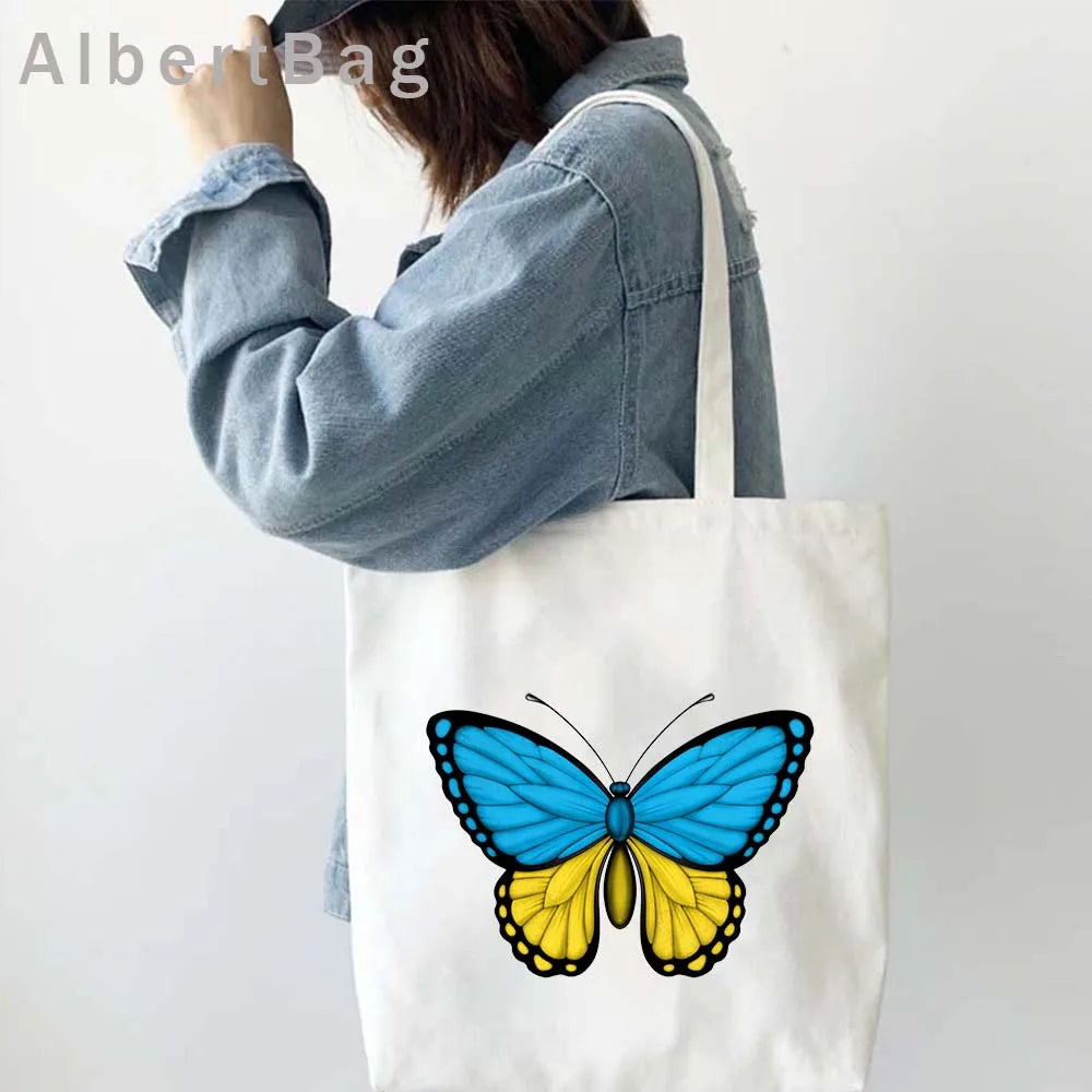 Woman carrying Ukrainian patriotic grocery tote with butterfly print.