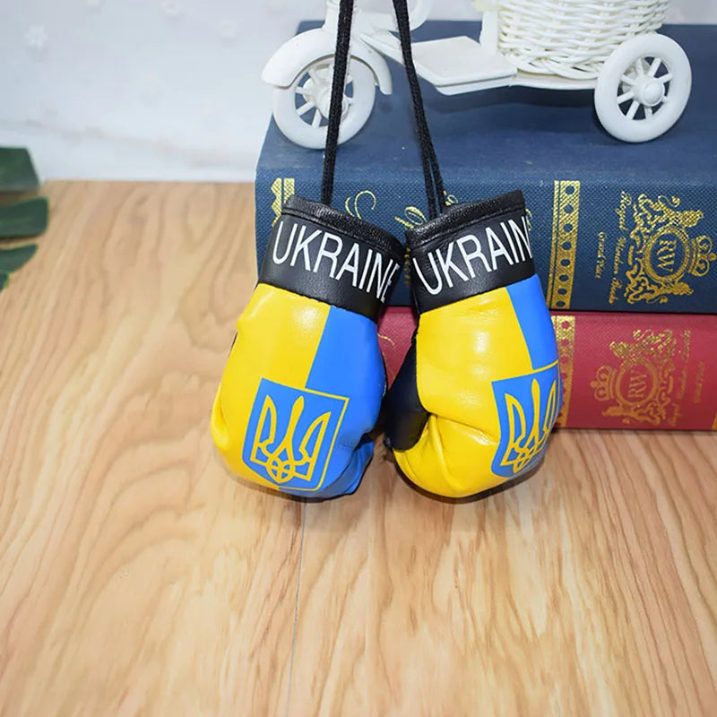 Ukraine flag boxing gloves keychains on books, showcasing vibrant national pride and unique accessory for patriotic enthusiasts.