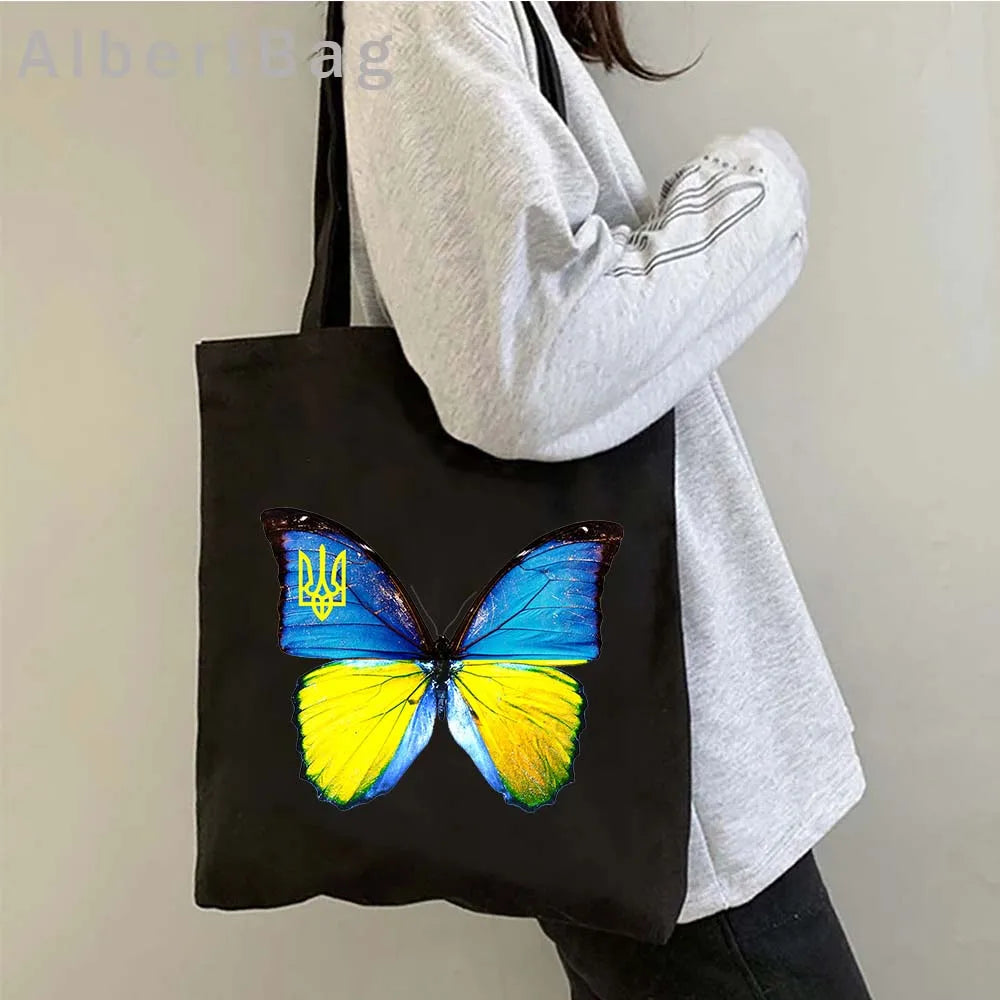 Person carrying Ukrainian patriotic grocery tote bag with a blue and yellow butterfly design