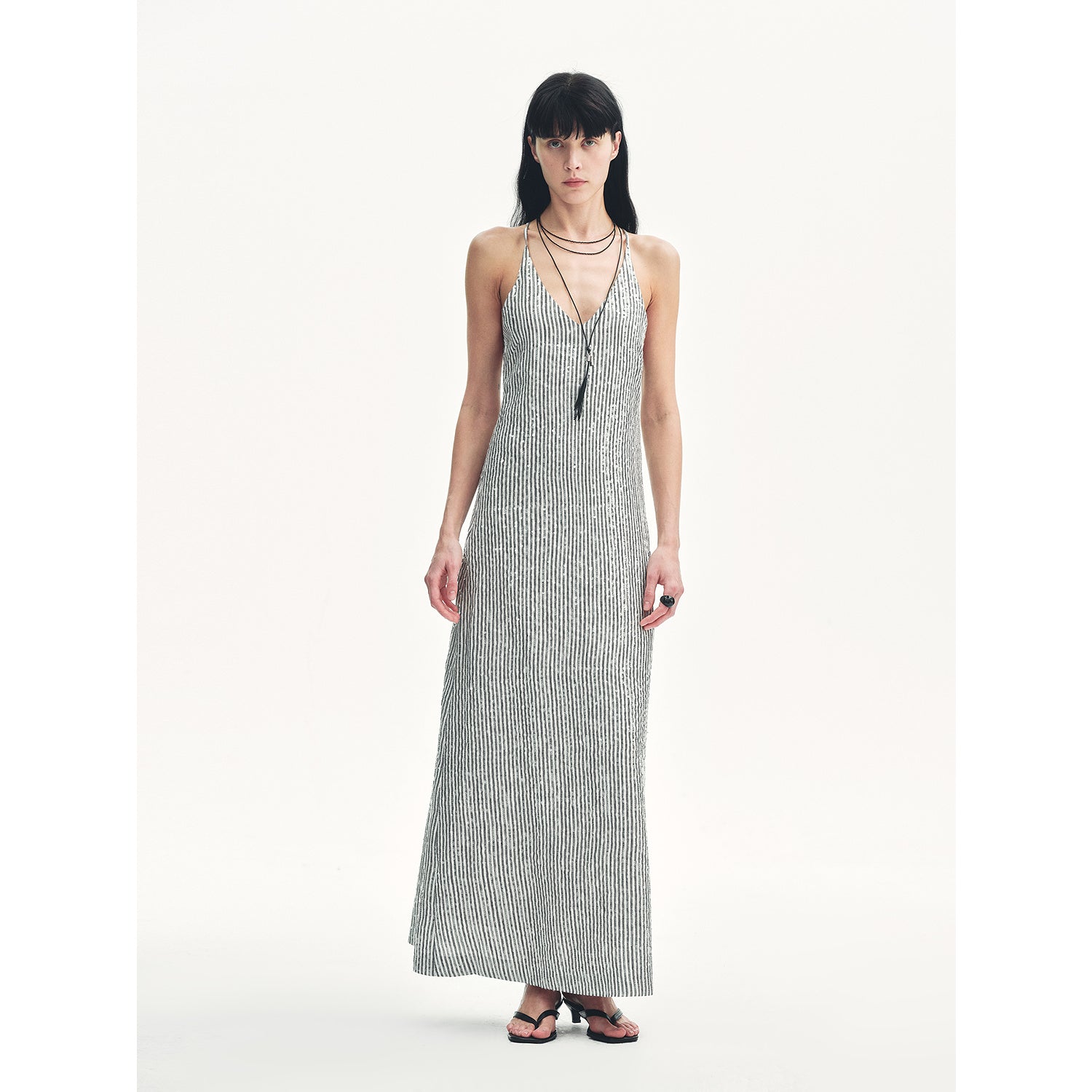 Model wearing Astrenya Sequin Linen Maxi Dress with V-neckline, delicate straps, and sequin embroidery, showcasing a modern elegant style.