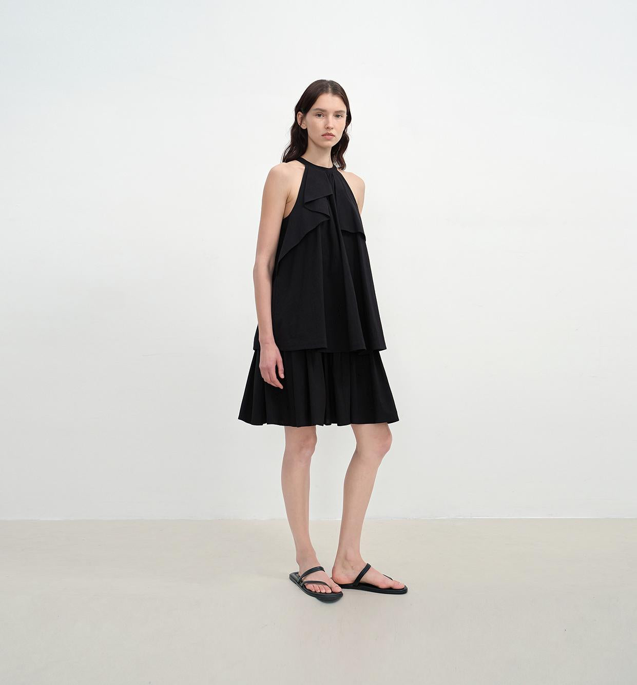 Woman wearing the Islanda Textured Cotton Halter Dress in black, featuring an A-line shape and pleated halter neckline.