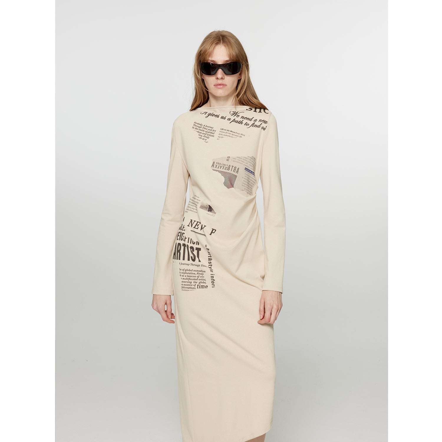 Model wearing City Frame Bias-Cut Dress with newspaper print, one-shoulder neckline, pleated waist, and asymmetrical silhouette.