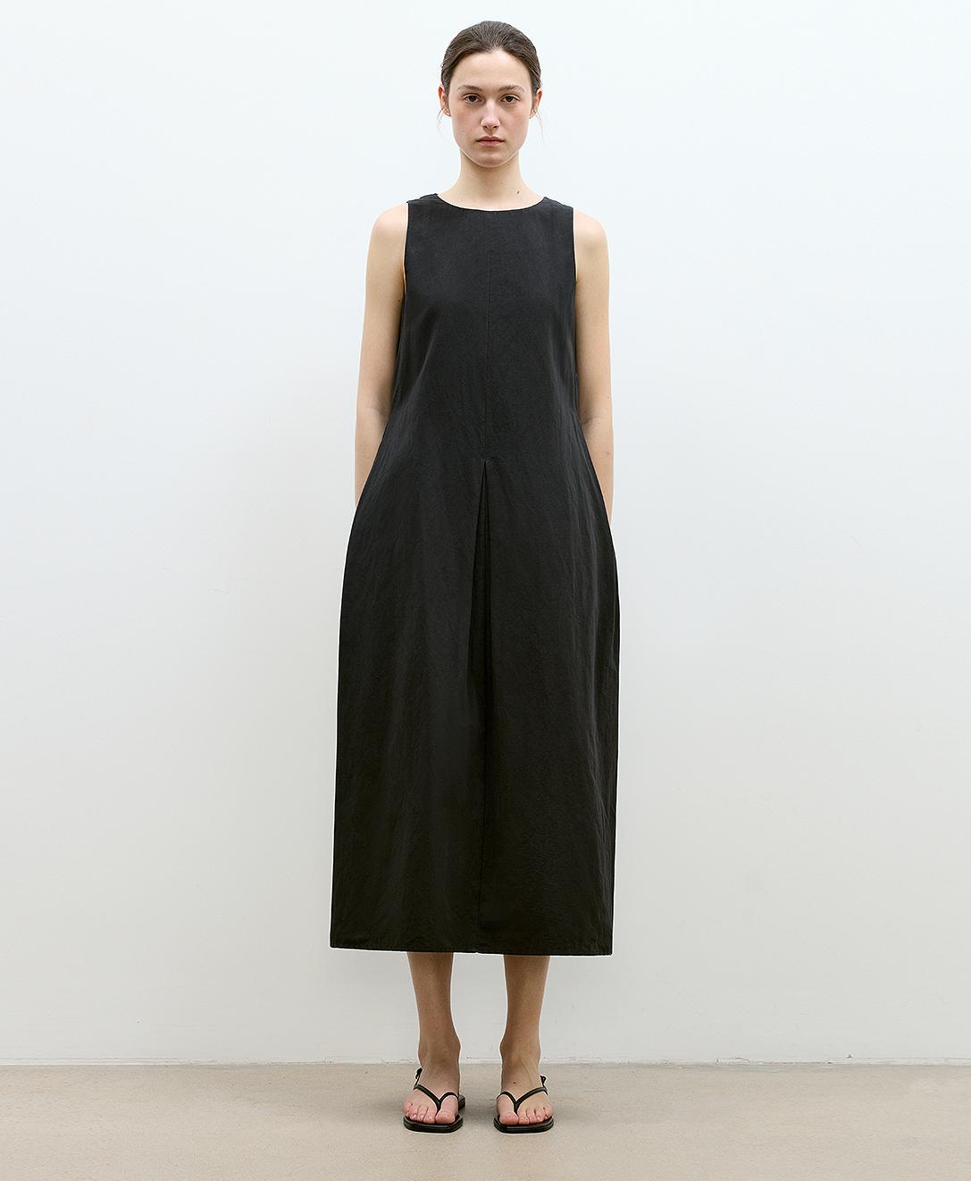 Model wearing black cotton-linen hourglass dress with U-neck and A-line skirt, showcasing elegant sculpted design.
