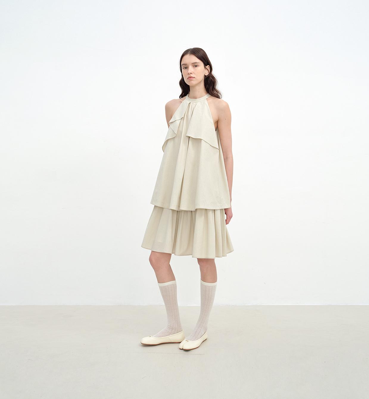 Model wearing Islanda Textured Cotton Halter Dress with pleated neckline, A-line shape, and mid-calf skirt in a neutral tone.