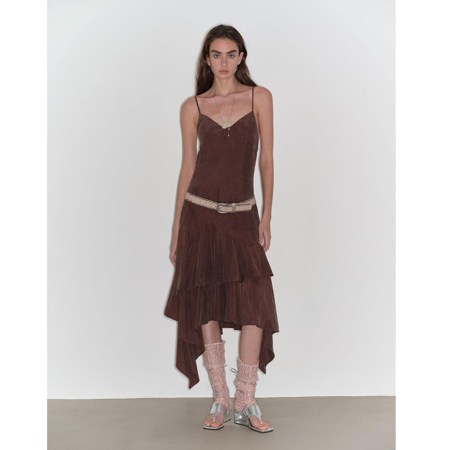 Model wearing Aravelle Draped Tie-Back Midi Dress with asymmetric hem in brown, styled with belt and sandals, showcasing elegant design.