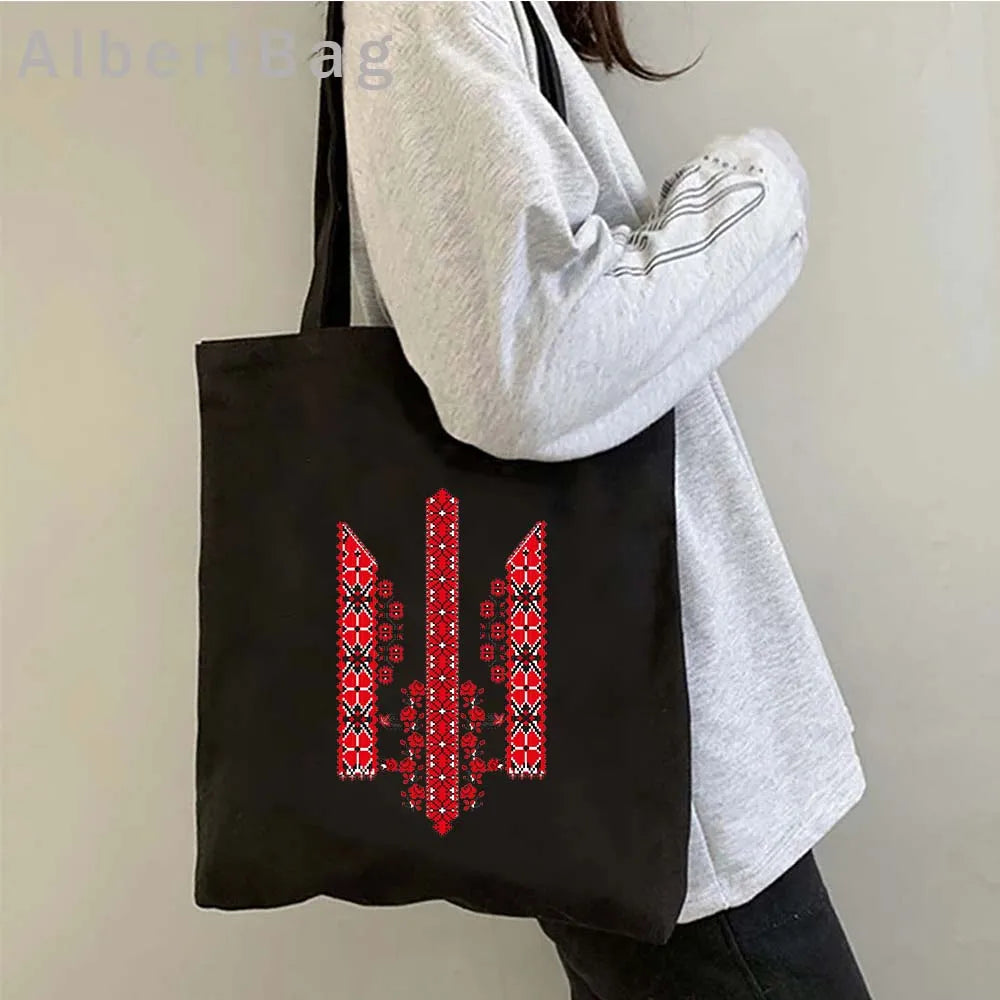 Woman carrying Ukrainian patriotic grocery tote bag with red patterned design.