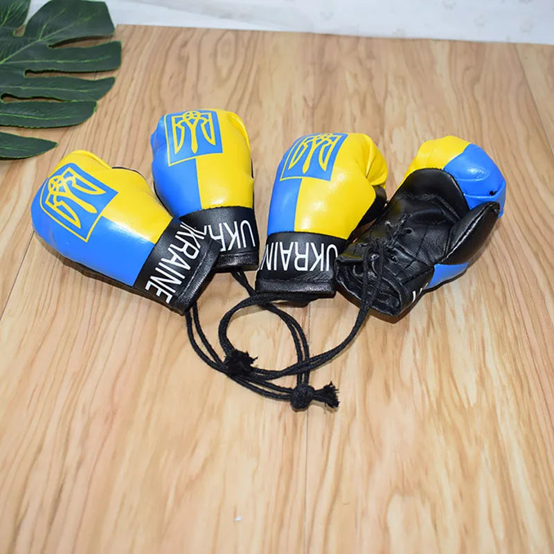 Ukraine flag boxing gloves keychains, vibrant design, patriotic symbol on a wooden surface.