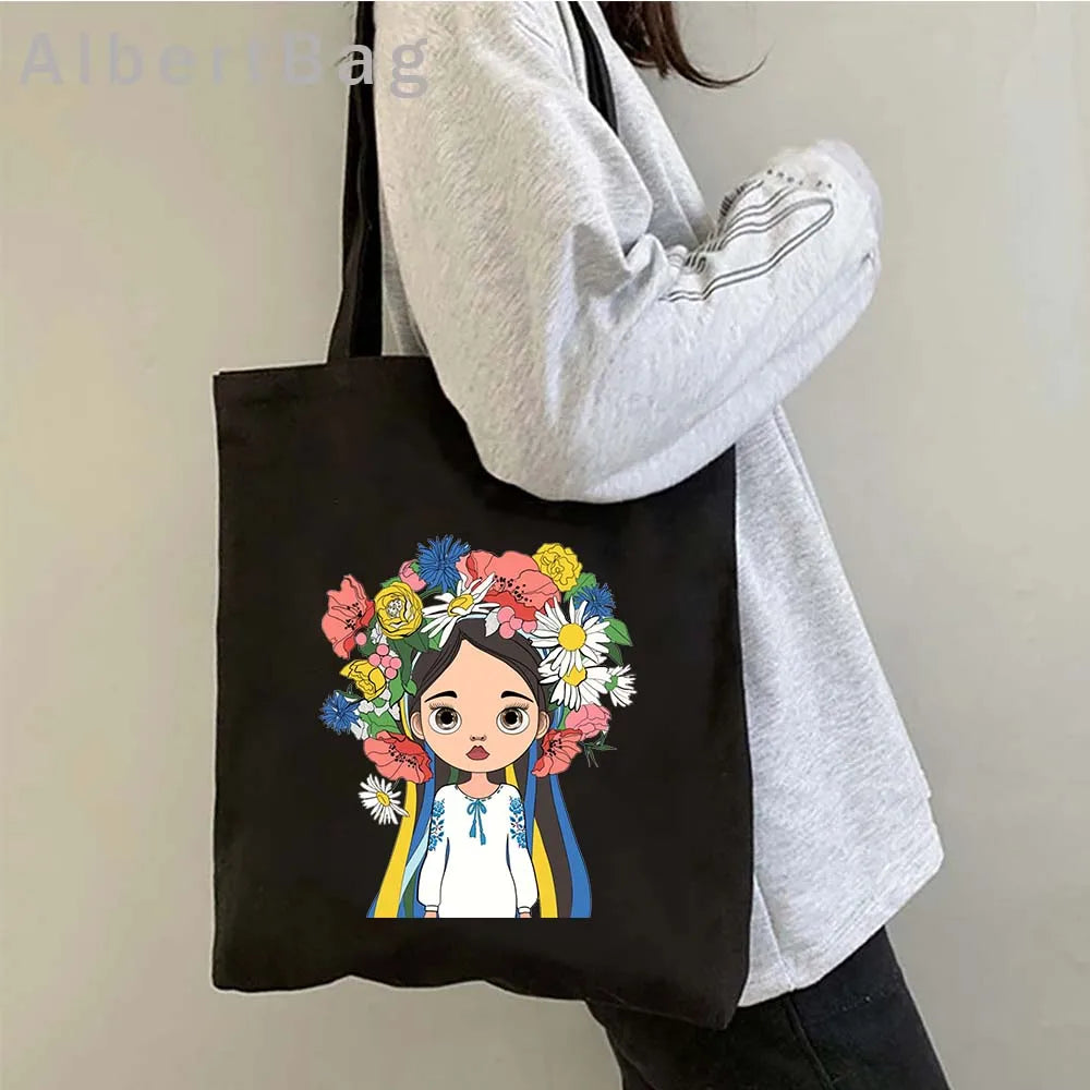 Ukrainian patriotic grocery tote bag with floral design, worn by person in a gray sweater