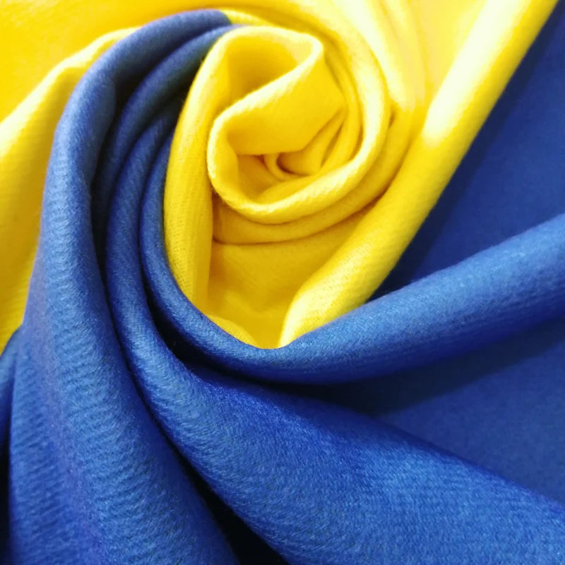 Close-up of designer cashmere shawl in Ukraine flag colors, showcasing luxurious yellow and blue fabric folds.