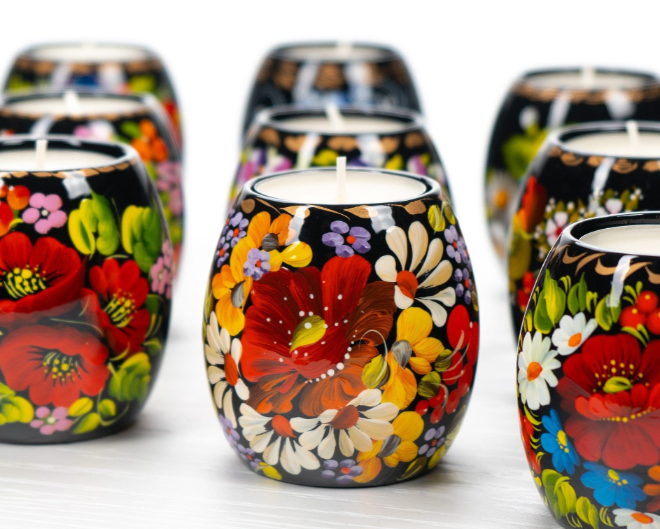 Hand-painted floral candles with vibrant flowers in red, yellow, and white, creating a colorful and artistic decorative display.