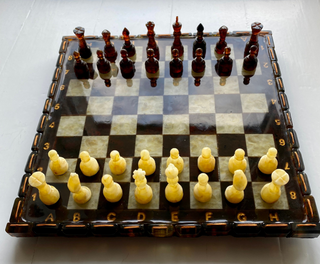 Vintage chess board with ivory and dark brown pieces set up for a game, viewed from above.