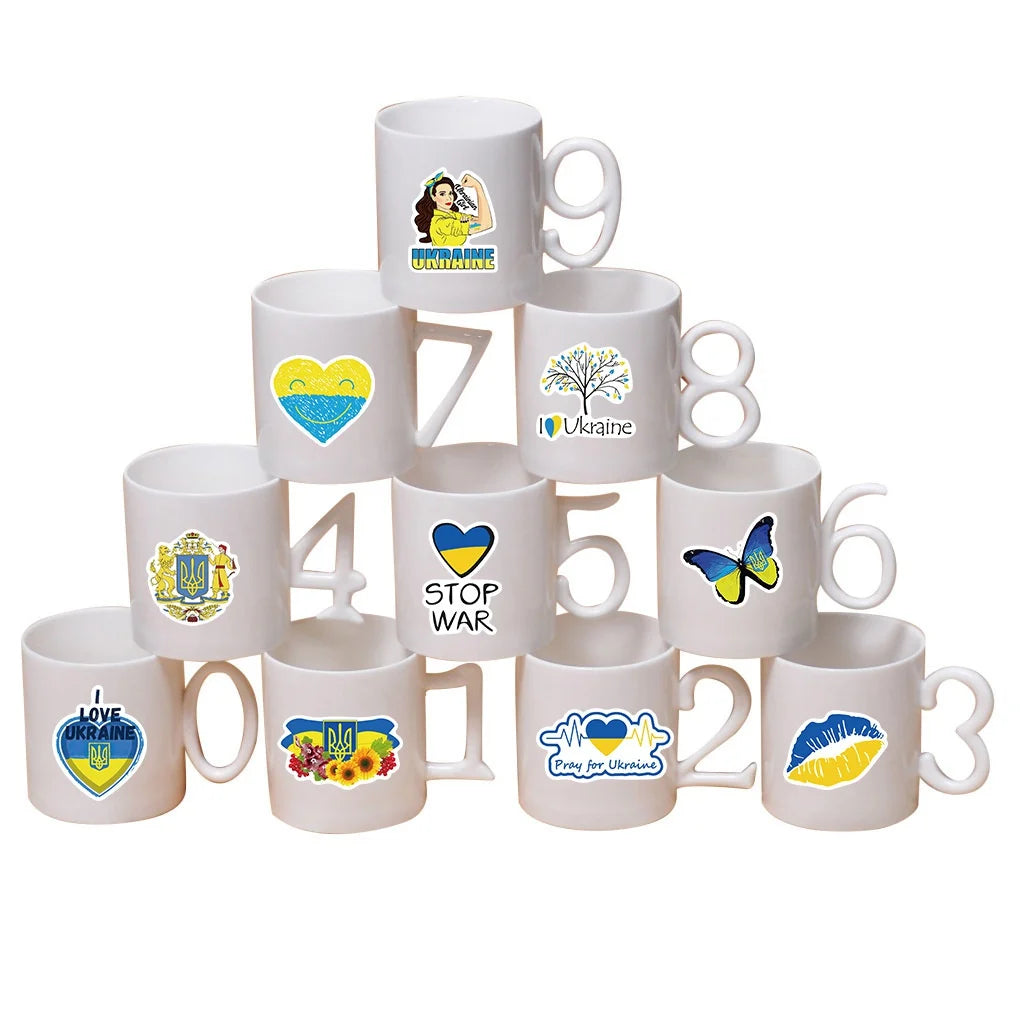 Stack of white mugs featuring various Ukraine-themed designs and messages, including "Stop War" and "I Love Ukraine."