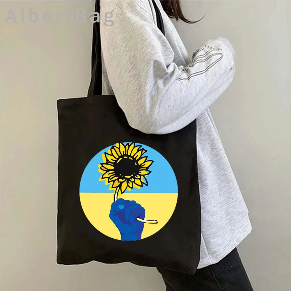 Ukrainian patriotic grocery tote with sunflower design held by person, eco-friendly and reusable cotton bag.