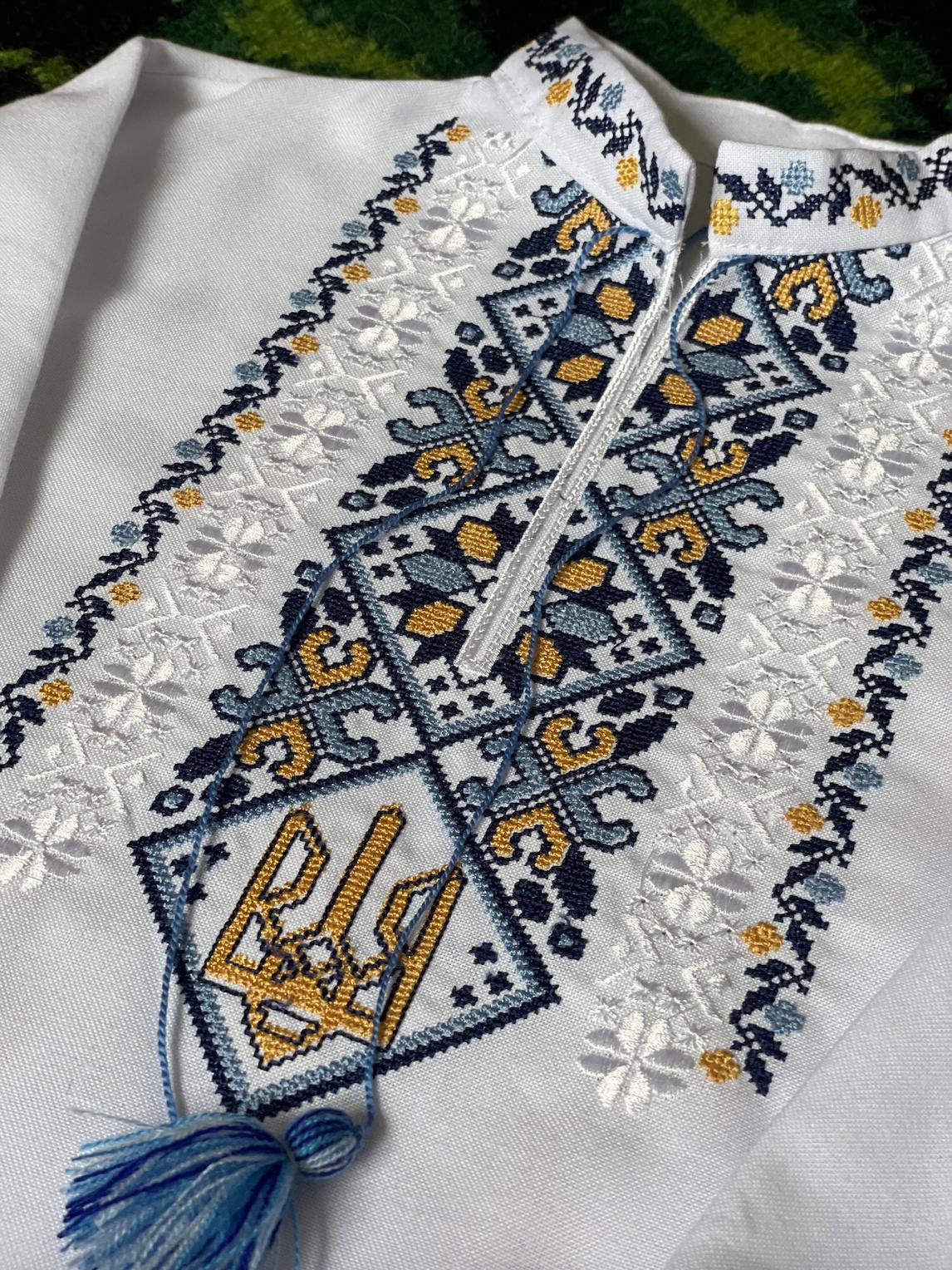 Close-up of boys’ vyshyvanka shirt with blue and yellow Tryzub embroidery, symbolizing Ukrainian heritage and identity.