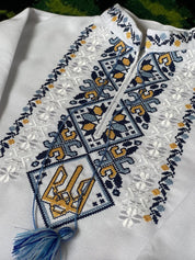 Close-up of boys’ vyshyvanka shirt with blue and yellow Tryzub embroidery, symbolizing Ukrainian heritage and identity.