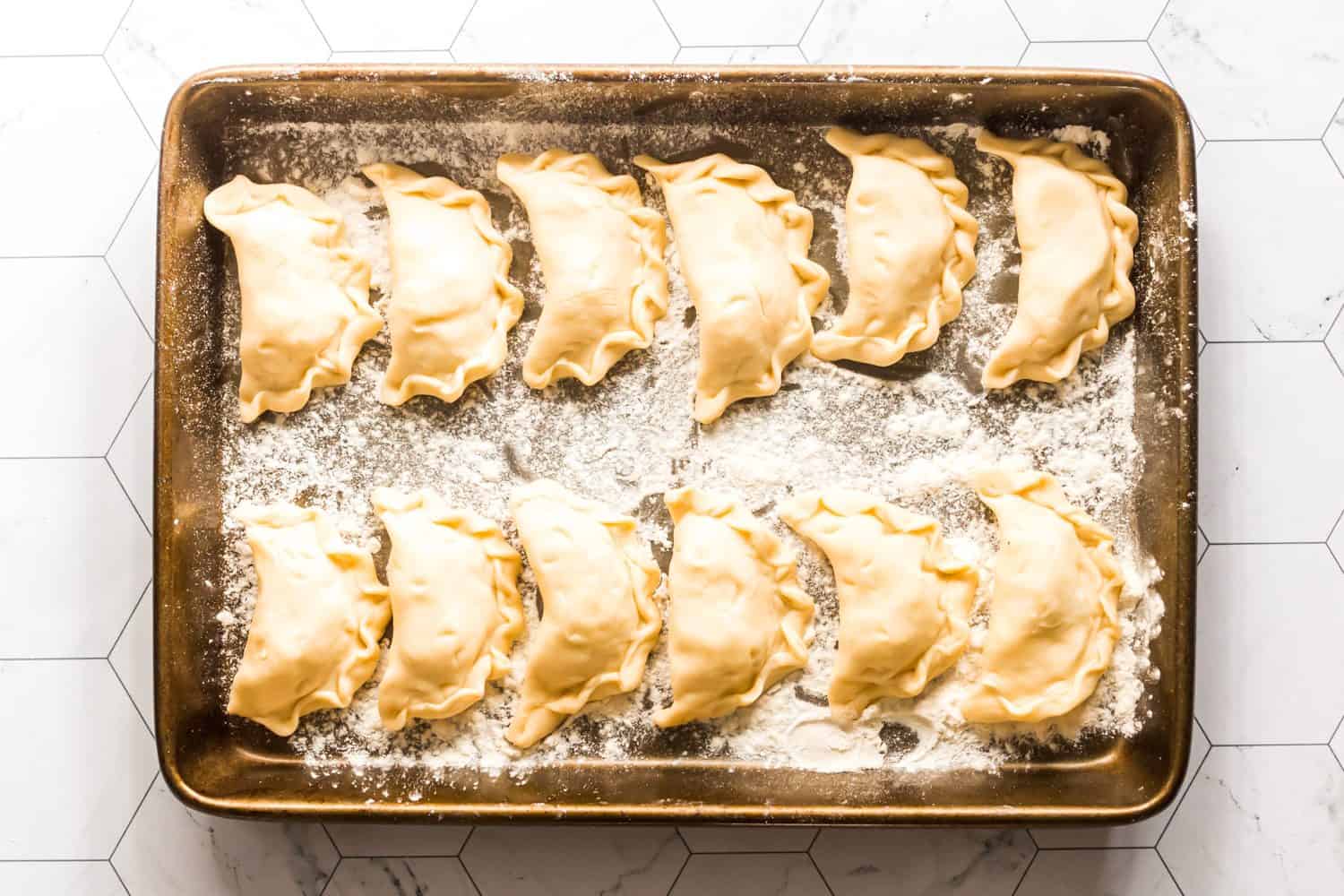 Homemade Ukrainian varenyky dumplings with potato, cabbage, or farmer’s cheese filling on baking tray, ready to cook.