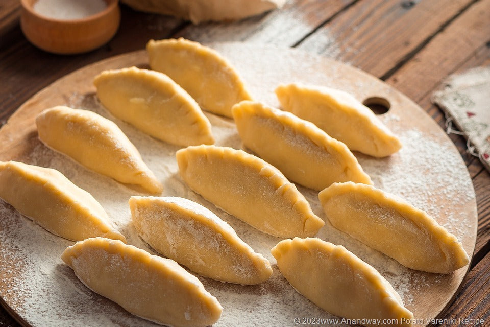 Handmade Ukrainian varenyky dumplings arranged on a floured wooden board, ready for cooking. Frozen potato, cabbage or cheese fillings.