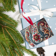 Ukrainian style acrylic ornament with floral design on a wrapped gift, featuring a red ribbon and surrounded by evergreen branches.