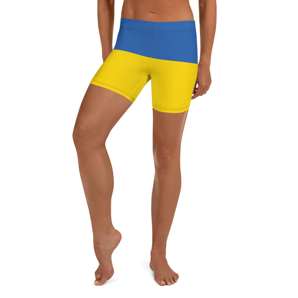 Woman wearing Ukrainian Flag shorts with blue and yellow design, part of Ukrainian Vibe Trizub Collection, featuring four-way stretch fabric.