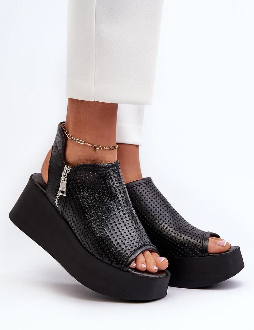 Alviera openwork leather sandals with zip closure, featuring an intricate cut-out pattern and black platform heel, worn with white pants.