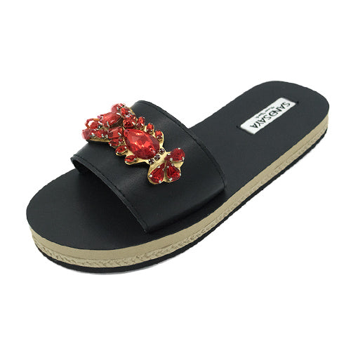 Black espadrille slide with vibrant red crystal embellishments, cushioned vegan leather surface, and reinforced strap.