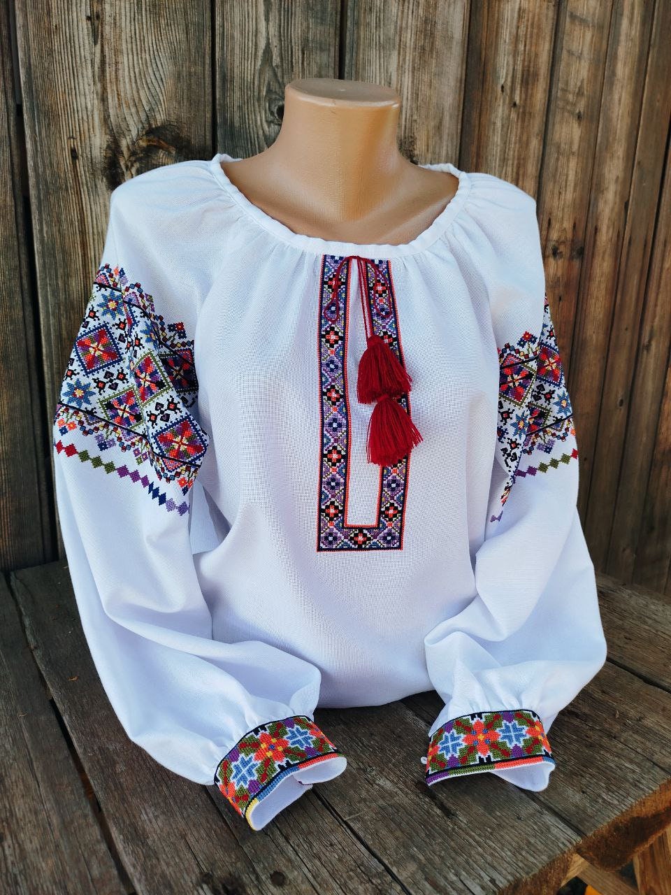 Traditional Ukrainian women's embroidered blouse on white fabric with colorful folk patterns, symbolizing cultural heritage.