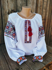 Traditional Ukrainian women's embroidered blouse on white fabric with colorful folk patterns, symbolizing cultural heritage.