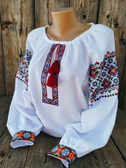 Ukrainian women's embroidered vyshyvanka blouse on white fabric, featuring traditional folk patterns and cultural symbolism.