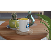 Irvelle ceramic mug with yellow accent on a wooden table, next to a small cactus and a decorative vase. 11 oz capacity.