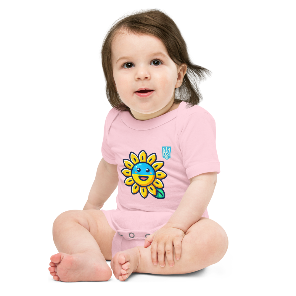 Baby wearing pink bodysuit with sunflower and Ukrainian flag design sitting on floor.