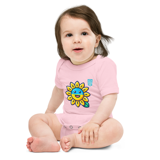 Baby wearing pink bodysuit with sunflower and Ukrainian flag design sitting on floor.