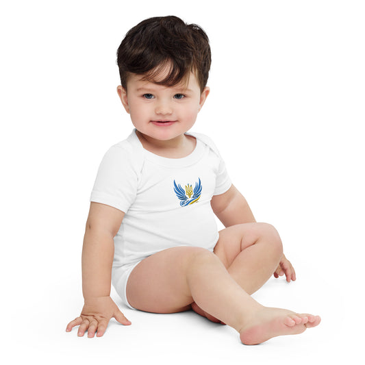 Baby wearing a white short sleeve one piece with a Ukrainian Tryzub logo, sitting on the floor and smiling.