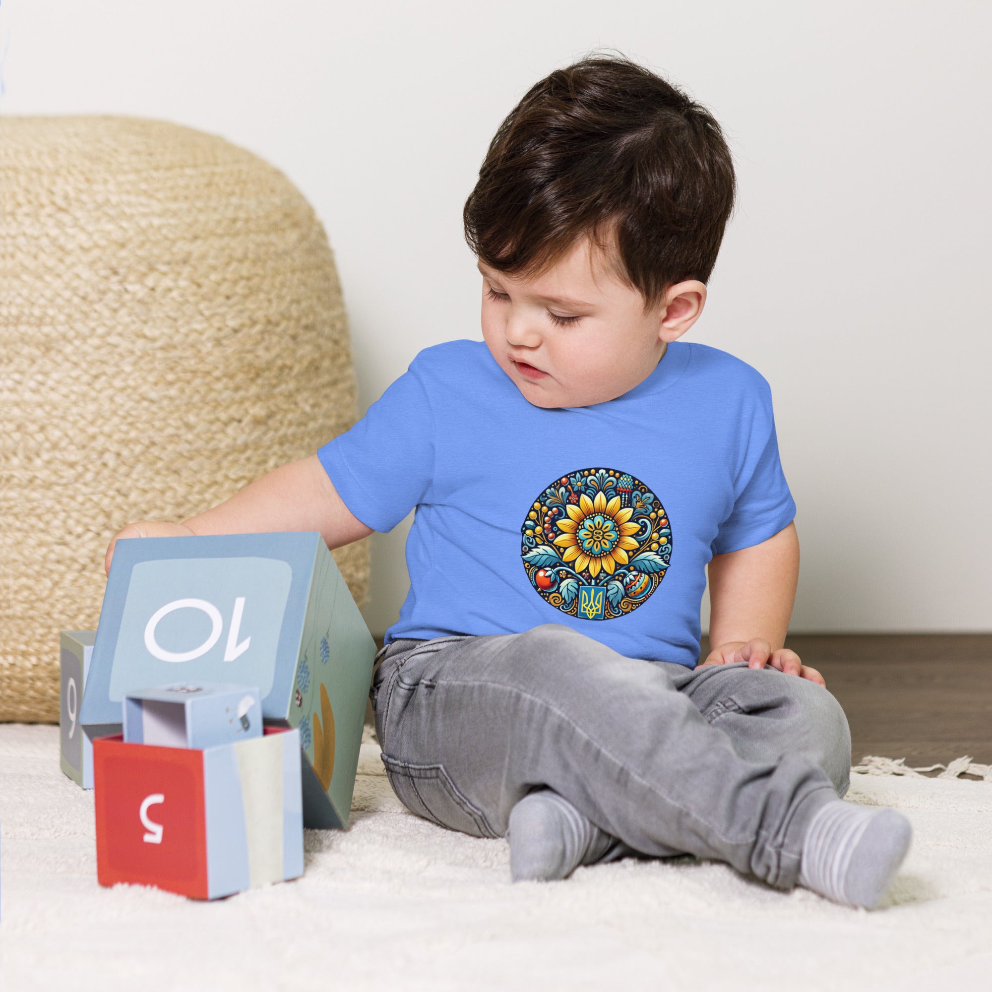 Baby wearing a blue short sleeve tee with Ukrainian symbol design, sitting near stacking blocks, 100% cotton for ultimate comfort.