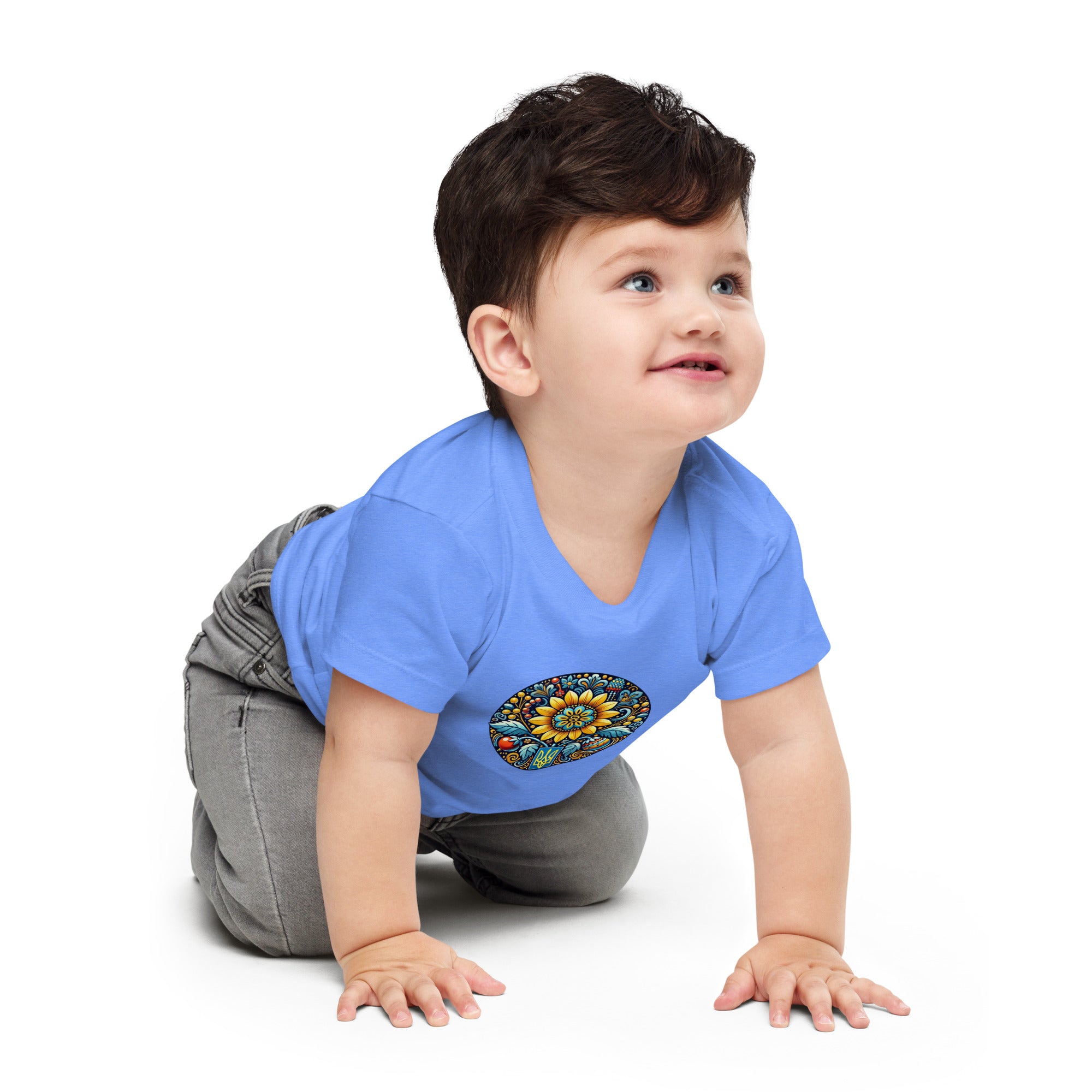 Baby wearing blue jersey tee with colorful Ukrainian symbol design, crawling on floor.