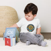 Toddler wearing baby jersey tee with Ukrainian symbols, playing with blocks.