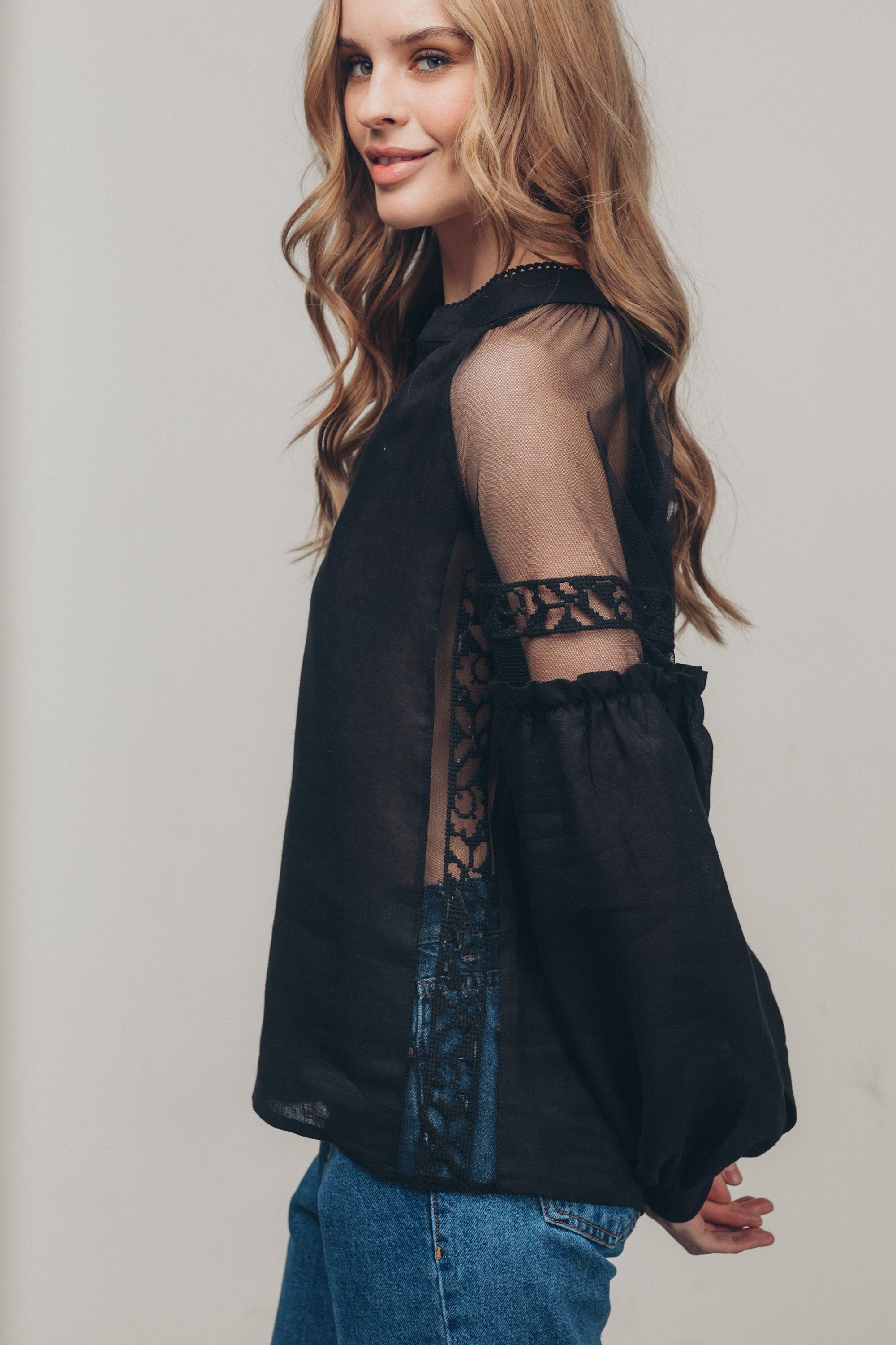 Black-on-black embroidered blouse in boho ethnic style with tulle shoulder inserts, modeled by a woman in casual setting.