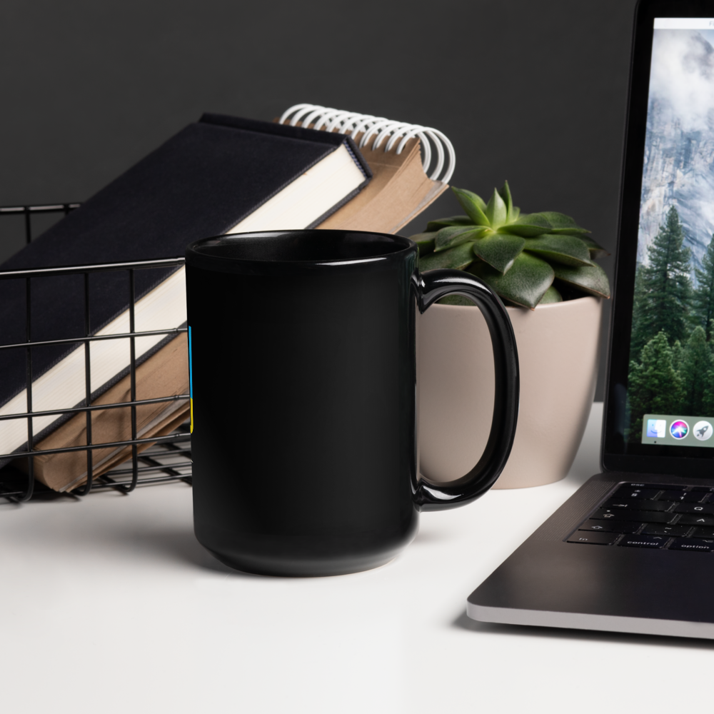 Black ceramic mug on desk beside laptop, books, and plant.