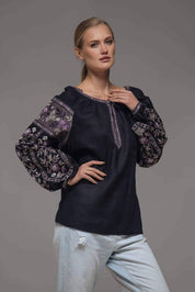 Woman wearing black linen embroidered blouse with traditional Ukrainian vyshyvanka design, featuring symbolic back ornament.