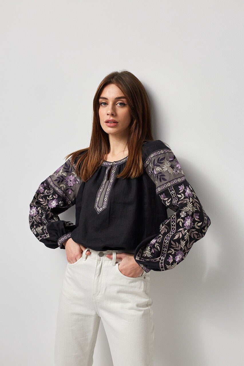 Woman wearing a black linen embroidered blouse, Ukrainian vyshyvanka style, with symbolic back ornament and traditional embroidery.