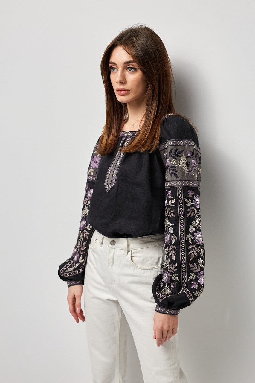 Black linen embroidered vyshyvanka blouse with Ukrainian symbolic ornament, worn by a woman.